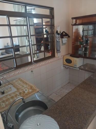 a kitchen with a sink and a counter with windows at Pousada Narcizo in São Lourenço
