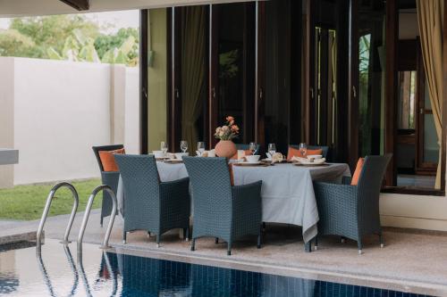 a dining room with a table and chairs next to a pool at The Villa - Private Pool near Tanjung Rhu Beach by WOW Holiday Homes in Kuah