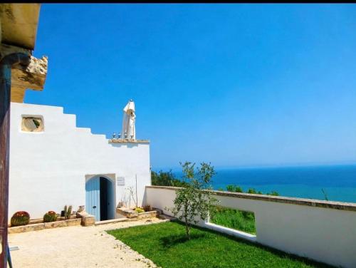 a white building with a blue door and the ocean at La Locanda Del Carrubo in Mattinata