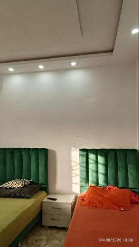 a bedroom with two beds with green headboards at Chalet Dar Well-Ness in Dar Mohammed Salah