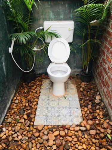 a bathroom with a toilet and some plants at LIVAA NEST Resort Mysore in Kālvādi