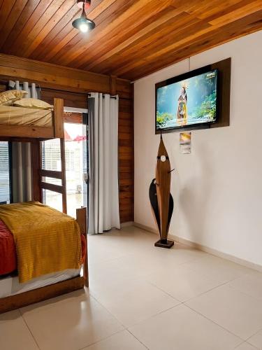a bedroom with a bed and a television on a wall at Pousada Canto Gira Sol Penha SC Estúdio Sol 5 Min do Beto Carrero in Penha