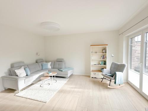 a white living room with a couch and two chairs at Ferienwohnung Knut in Bornholt