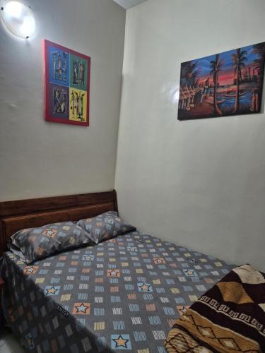a bedroom with a bed and two pictures on the wall at SEN-HOME Free in Dakar