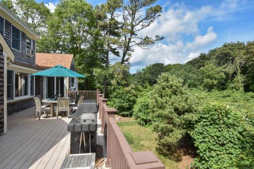 a wooden deck with a table and an umbrella at 1 6 mi to Nauset Beach in Orleans
