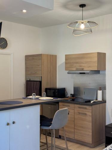 a kitchen with wooden cabinets and a table with a chair at Le Nid Malouin in Saint Malo