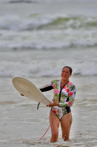 a woman walking in the water with a surfboard at Kuma Surf Camp in Arugam Bay
