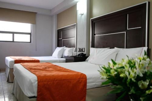 a hotel room with two beds and flowers in it at Hotel Estadio in Guadalajara