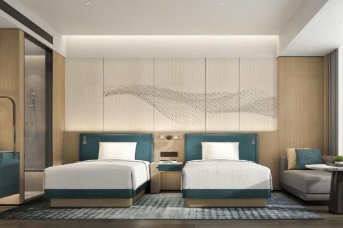 a bedroom with two beds and a couch at Courtyard by Marriott Rizhao in Rizhao