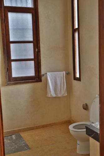 a bathroom with a toilet and a window and a towel at Dar TOUFTEN in Agouni