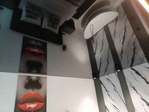 a floor lamp in a room with red lips on a wall at HERA Elysium Apartament EROS in Sinaia