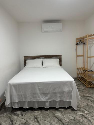 a bed in a white room with a white bedspread at FRAN's - HOSPEDAGENS in Lagoa Santa
