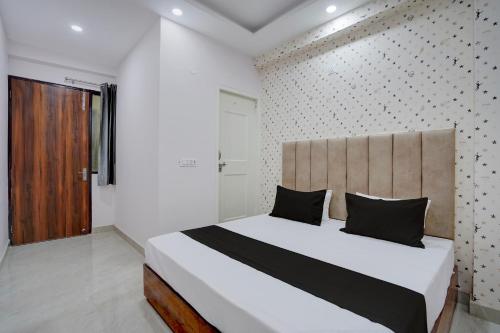 a bedroom with a large white bed with black pillows at Hotel O Rooftop Inn in New Delhi
