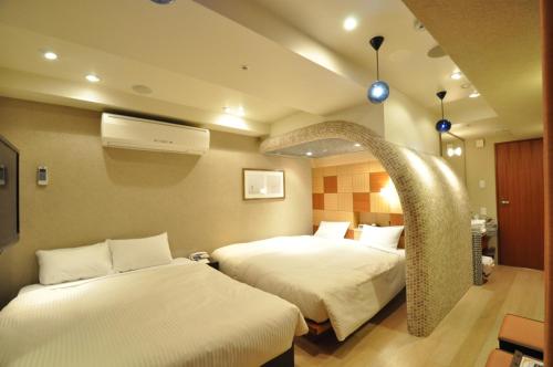 a hotel room with two beds and a fan at Hotel Mid In Kawasaki Ekimae in Kawasaki