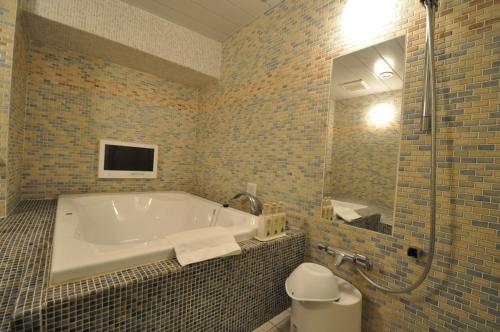 a bathroom with a tub and a toilet and a mirror at Hotel Mid In Kawasaki Ekimae in Kawasaki