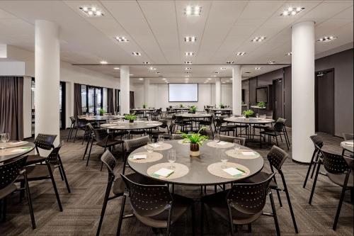 a restaurant with tables and chairs and a projection screen at Hôtel Alt Québec in Quebec City