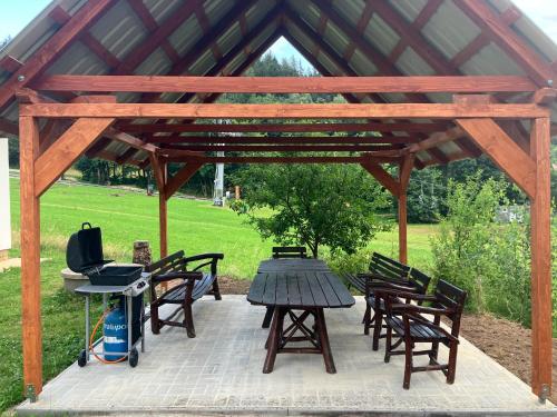 a picnic table and chairs under a wooden pavilion at Chalupa a apartmány Lojka in Benecko