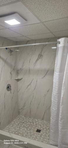 a bathroom with a shower with white marble walls at Red Carpet Inn Williamstown in Williamstown