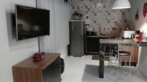 a living room with a television and a kitchen with a table at Ertal House in Blumenau
