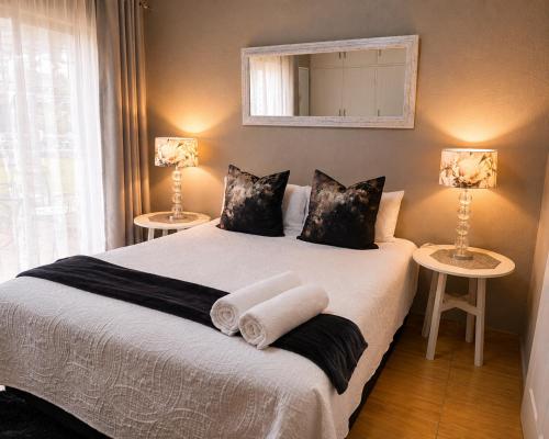 a bedroom with a bed with two lamps and a mirror at Zhantique Guest House 2- Unit 5 in Boksburg
