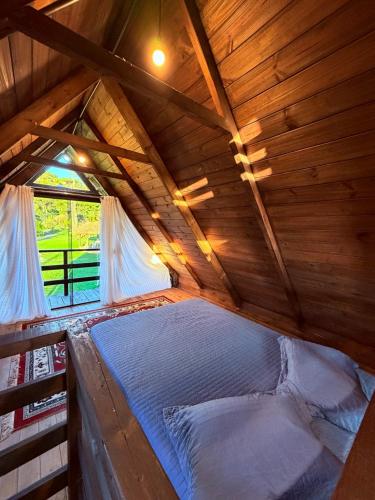 a bed in a wooden cabin with a window at Pousada refúgio do lago in Lages