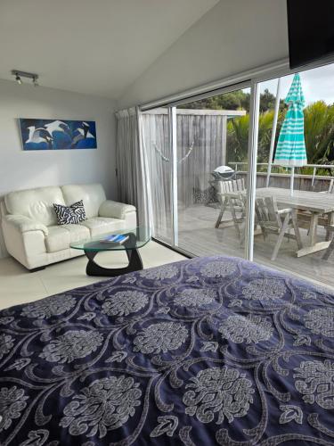 a living room with a bed and a couch at The Nikau Loft in Onetangi