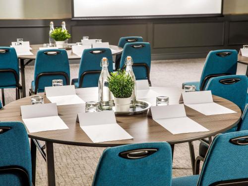 a conference room with tables and blue chairs at Mercure Birmingham West Hotel in West Bromwich