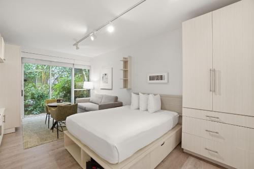 a white bedroom with a bed and a desk at Placemakr Dupont Circle in Washington, D.C.