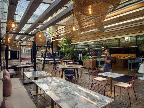 a restaurant with tables and chairs and a person walking in the background at Novotel Santiago Las Condes in Santiago