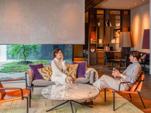 two men sitting on chairs in a living room at Pullman Tokyo Tamachi in Tokyo