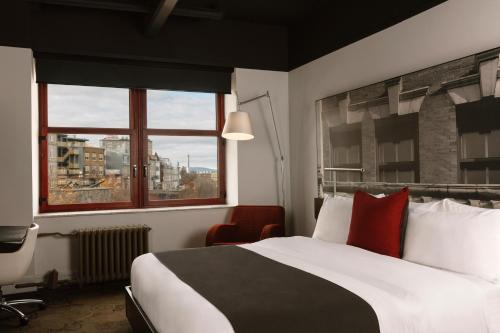 a hotel room with a large bed and a window at Hôtel Le Germain Québec in Quebec City