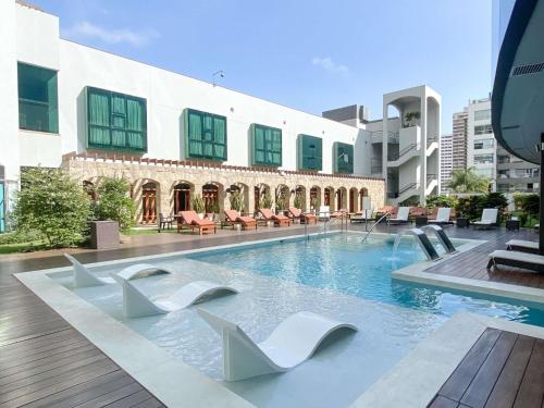 a swimming pool with white chairs in a building at Swissotel Lima in Lima