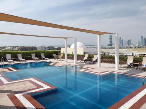a swimming pool on the roof of a building at Mövenpick Hotel Apartments Al Mamzar Dubai in Dubai