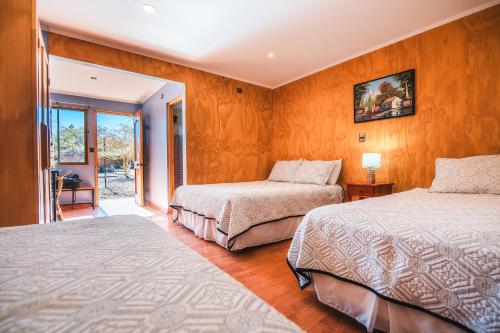 two beds in a room with wooden walls at Hotel Iorana Tolache in San Pedro de Atacama