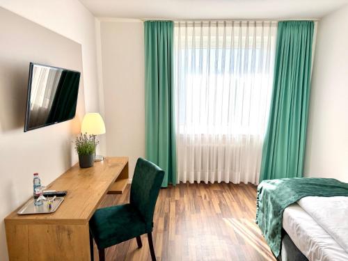 a bedroom with a desk and a bed and a window at Stadthotel Langenfeld in Langenfeld