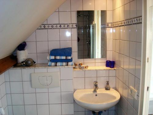 a white tiled bathroom with a sink and a mirror at Bed en Boterham in Hedel