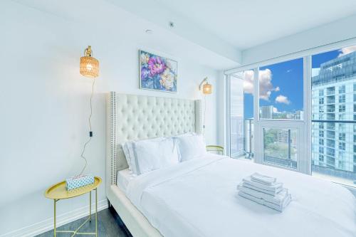 a bedroom with a white bed and a large window at Filmos Hotel and Suites in Toronto