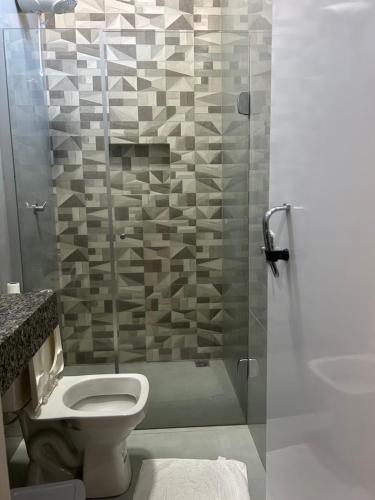 a bathroom with a toilet and a glass shower at Rafa Plaza Hotel in Cassilândia