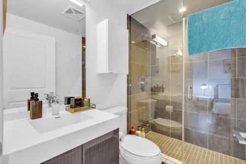 a white bathroom with a toilet and a shower at Filmos Hotel and Suites in Toronto