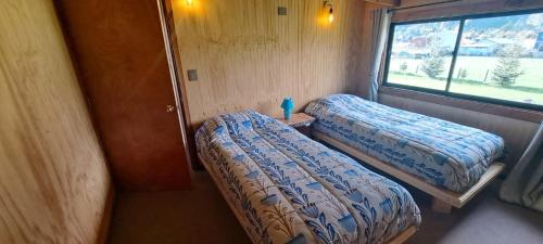 a small room with two beds and a window at Cabañas Llifén Costanera in llifen