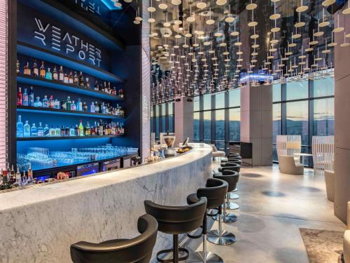 a bar with a row of stools in a building at Pullman Tbilisi Axis Towers in Tbilisi City