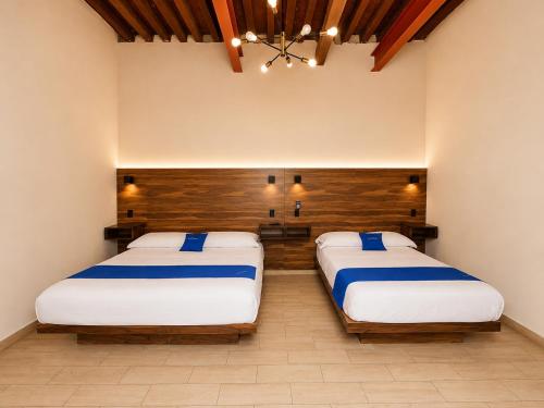 two beds sitting in a room with at Hotel Queretaro in Querétaro
