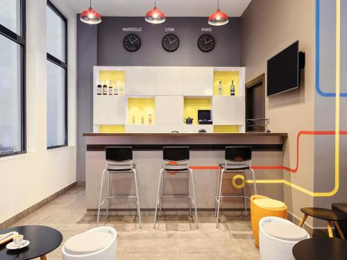 a bar in a restaurant with stools and clocks on the wall at ibis Styles Marseille Gare Saint-Charles in Marseille