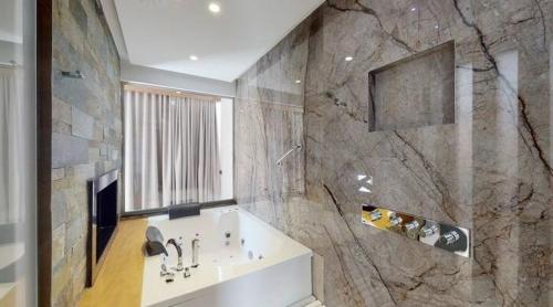 a bathroom with a sink and a large stone wall at Bliss Properties Jacuzzi Suite Free Pool Access in Draç