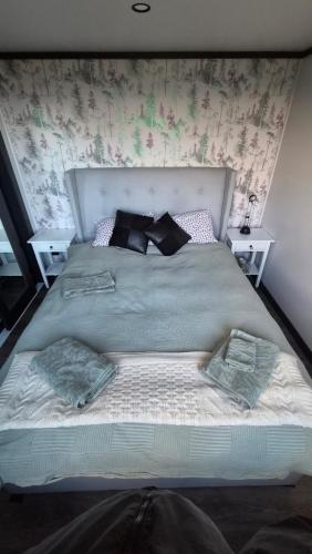 a large bed with pillows on it in a bedroom at Frogs Hollow in Greytown
