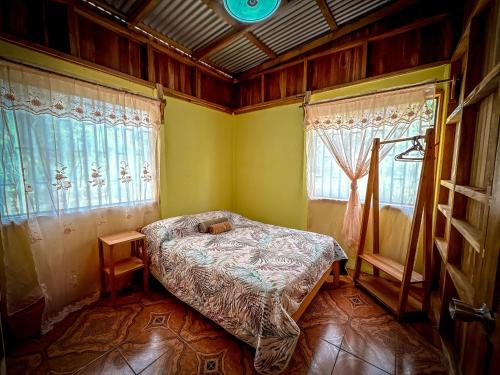 a bedroom with a bed in a room with windows at Casa Chilamate in Puerto Jiménez