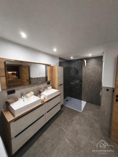 a bathroom with two sinks and a shower at PS-Apartment Luis in Vorderthiersee