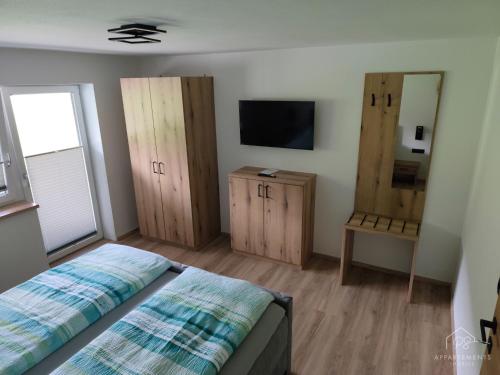 a bedroom with a bed and a tv and wooden cabinets at PS-Apartment Luis in Vorderthiersee