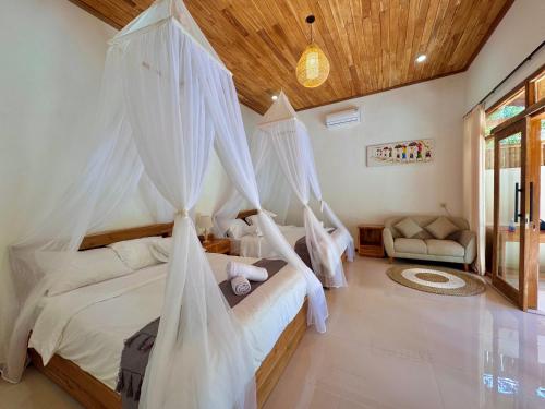 two beds in a bedroom with mosquito nets at AVYANA sanctuary in Gobleg