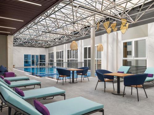 a lobby with tables and chairs and a pool at Mercure Riyadh Al Anoud in Riyadh